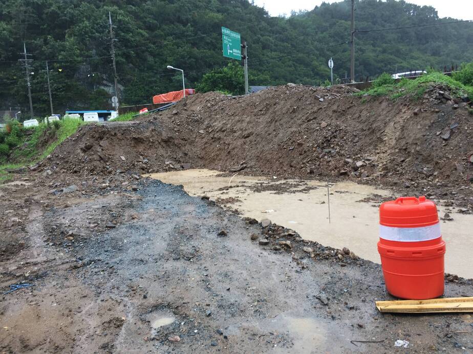 도로 옆면이 절개 되어 있고 흙탕물이 가득 차있는 모습