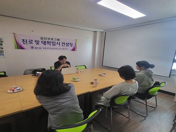 현수막(집단프로그램 진로 및 대학입시 컨설팅 꿈드림 장흥군학교밖청소년지원팀)이 걸린 상담실에서 청소년들이 컨설팅을 받고 있는 모습