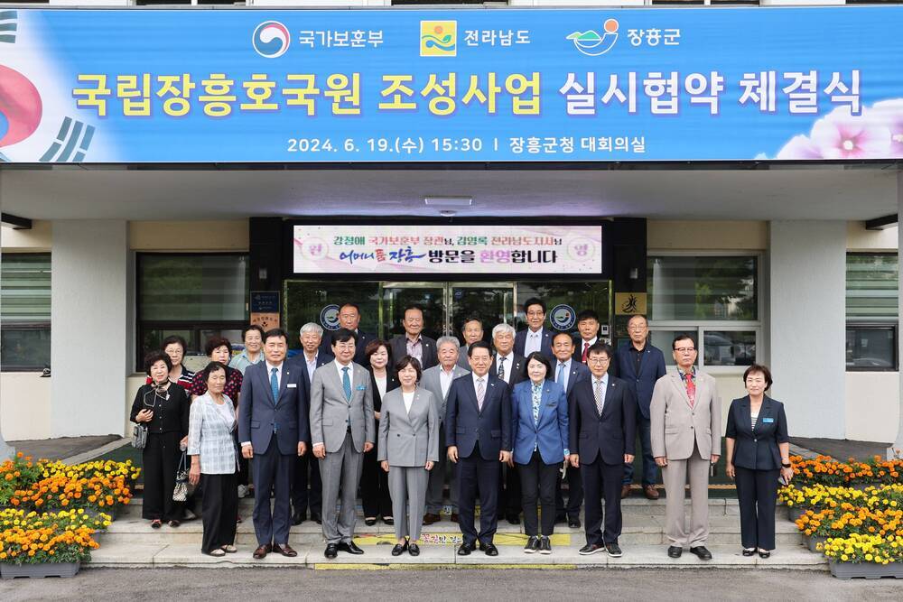 국립장흥호국원 조성사업 실시협약 체결식 2024.6.19(수) 15:30 장흥군청 대회릐실 현수막을 위에 걸고 건물앞에서 다함께 사진찍는 관계자들